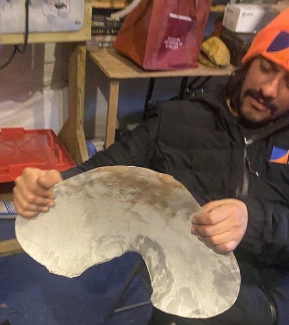 Ein Mann hält ein aufgerissenes Metallstück in beiden Händen